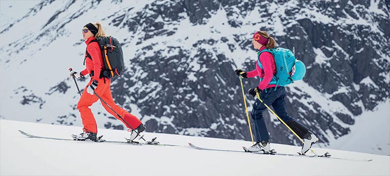 couple of ladies ski mountaineering with avalanche airbag backpacks on
